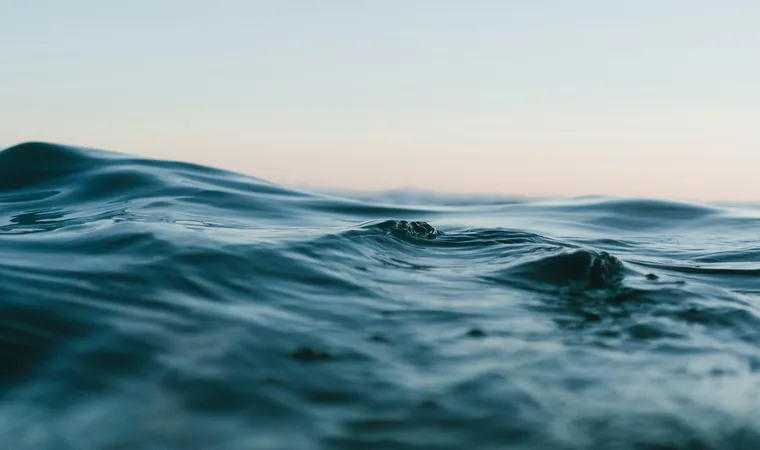 Soft blue ocean waves beneath a pale, open sky