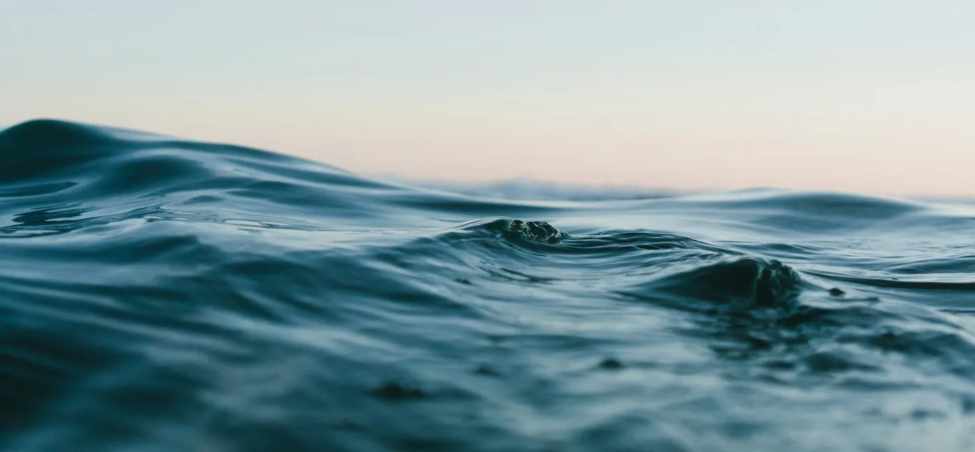Soft blue ocean waves beneath a pale, open sky